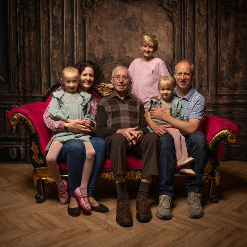 Multi-generation family portrait with grandfather, parents, and three children during a 90th birthday celebration photoshoot.