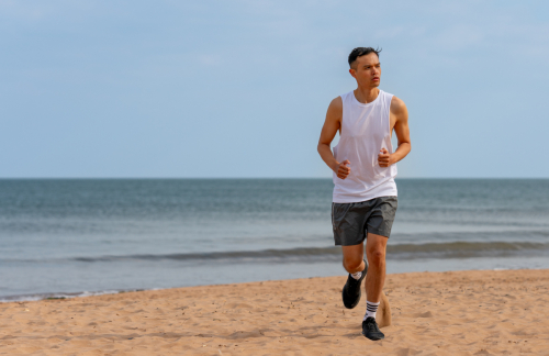 Athletic male model running on sandy shoreline