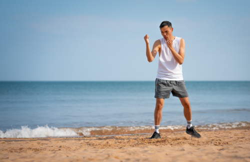 Action pose Muay Thai training on sandy beach at Dawlish Warren