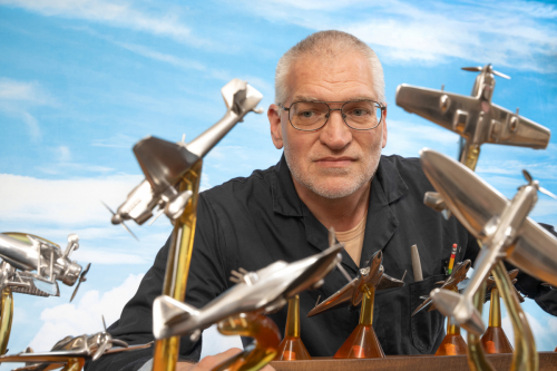 Second angle of Robert Millis peering between his aluminium sculptures, showcasing aircraft detail.