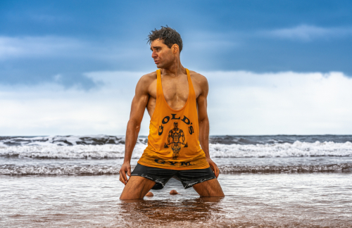Male model poses dramatically, kneeling in shallow water at Sidmouth Beach