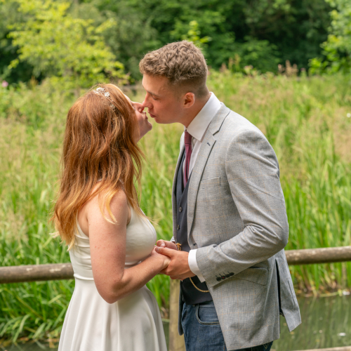 Bride and groom holding hands and about to kiss at Nine Springs, Yeovil