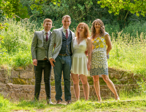 Full group portrait of four smiling wedding guests at Nine Springs, Yeovil